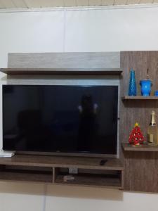 uma televisão de ecrã plano sentada num centro de entretenimento em madeira em Casa Livramento Rivera diária em Santana do Livramento