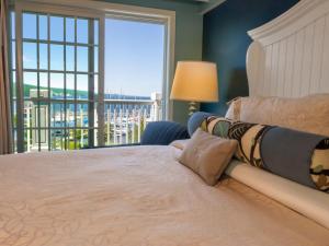 a woman laying on a bed in a bedroom with a window at Watkins Glen Harbor Hotel in Watkins Glen