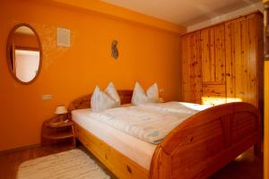 a bedroom with a wooden bed with an orange wall at Naturlaub.pur in Waldmünchen
