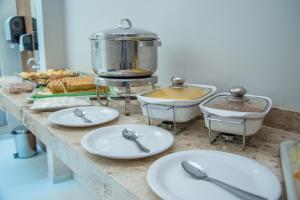 a kitchen counter with white plates and a pot at Hotel e Pousada Flor do Juá in Juazeiro do Norte