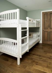 two white bunk beds in a room with a wooden floor at Courtyard at Crail in Crail