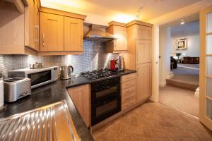 uma cozinha com armários de madeira e um forno com placa de fogão em Oberon River View Apartment em Bourton on the Water