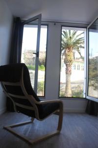 une chaise assise devant une fenêtre avec un palmier dans l'établissement Casa da Ponte Casa familiar, à Nordeste