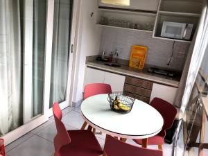 une petite cuisine avec une table blanche et des chaises rouges dans l'établissement Apto Novo no melhor d Pipa, à Pipa
