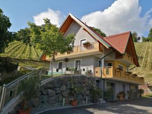 a house with a balcony and a stone wall at Ferienwohnung Stoff in Kitzeck im Sausal