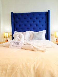 a large bed with a blue headboard and white sheets at VENICE by luxury Atitlan in San Pedro La Laguna