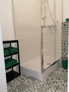 a bathroom with a shower and green towels on a tile floor at Mieszkanie Konin Zatorze in Konin