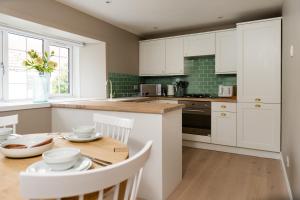a kitchen with white cabinets and a wooden table at Courtyard at Crail in Crail