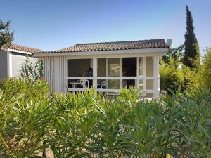 a small house with a person sitting on a porch at Camping Hameau Des Cannisses in Gruissan