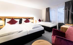 um quarto de hotel com duas camas e uma cadeira em Alpenhotel Schlüssel em Andermatt