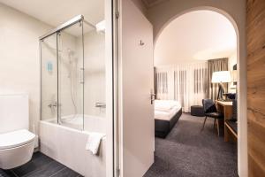 a bathroom with a shower and a toilet and a bed at Alpenhotel Schlüssel in Andermatt +47 photos