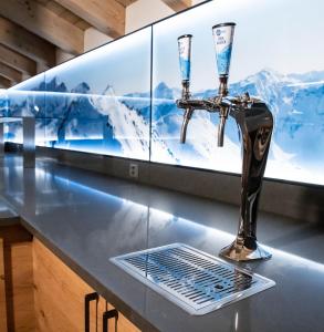 un robinet sur un comptoir avec deux verres à vin dans l'établissement Alpenhotel Schlüssel, à Andermatt