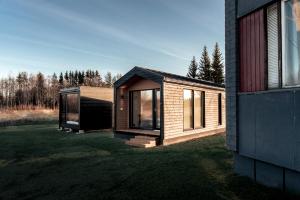 a small wooden house on a lawn next to a building at Black Hotel in Kempele