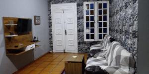 uma sala de estar com um sofá e uma TV em Casa Praia dos Anjos - 50m da praia em Arraial do Cabo