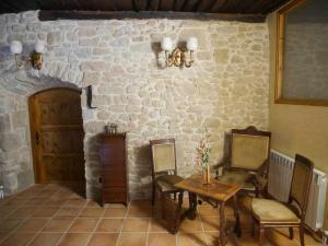 a room with a table and chairs and a stone wall at El Bressol de Cal Feixas in Freixinet