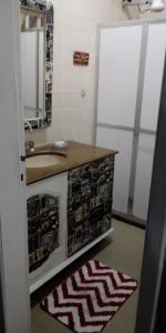 uma casa de banho com um lavatório, um espelho e um tapete em Casa Praia dos Anjos - 50m da praia em Arraial do Cabo