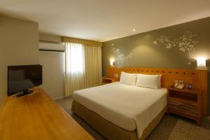 um quarto com uma cama e uma televisão de ecrã plano em Blue Tree Towers Fortaleza Beira Mar em Fortaleza
