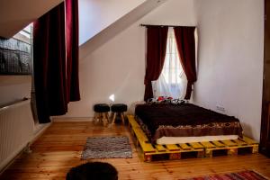 a bedroom with a bed and a window with red curtains at Pensiune agroturistica Casa cu Povesti Rau Sadului in Rau Sadului