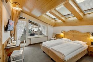 a bedroom with a large bed in a room with skylights at Hotel Antika in Zermatt