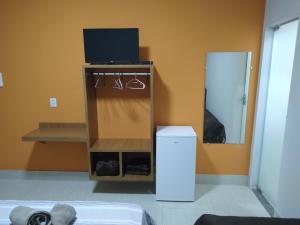 a room with a tv on a stand with a trash can at Sítio Pé da Serra - Pousada Rural in Capitólio