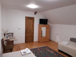 een woonkamer met een bank, een tafel en een televisie bij Agropensiunea Căprioara in Mintia