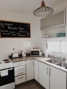 a kitchen with white cabinets and a chalkboard on the wall at Rincón Tigre in Tigre