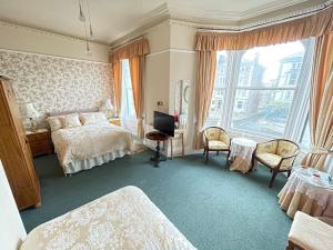 a bedroom with a bed and a desk and a window at White Court Llandudno in Llandudno