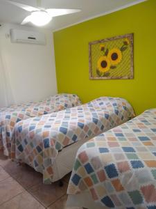 two beds in a room with a painting on the wall at Brejatuba Residence! Conforto e lazer em excelente condomínio in Guaratuba
