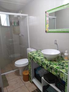 a bathroom with a sink and a toilet and a mirror at Brejatuba Residence! Conforto e lazer em excelente condomínio in Guaratuba