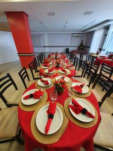 a long table with red tables and chairs with plates and napkins at Hotel São Bento in Marabá