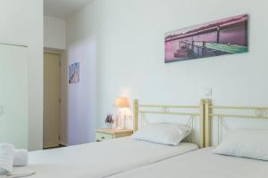 Duas camas brancas num quarto com uma fotografia na parede em Limani em Andiparos