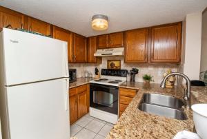 a kitchen with wooden cabinets and a white refrigerator at Unit 8213 - Ocean & Racquet Resort in Saint Augustine Beach