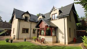 una casa blanca con techo negro en Culliss House B&B, en Inverness