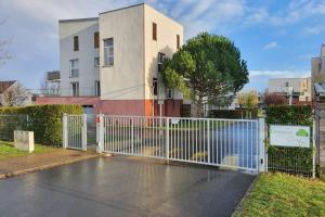 a white fence in front of a building at Appartement contemporain rénové à neuf avec cuisine équipé - Val de reuil in Val de Reuil