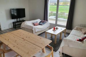 ein Wohnzimmer mit einem Tisch und einem TV in der Unterkunft Appartement contemporain rénové à neuf avec cuisine équipé - Val de reuil in Val de Reuil