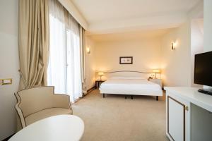 una camera con un letto e due sedie e una televisione di Hotel Ariston Molino Buja ad Abano Terme