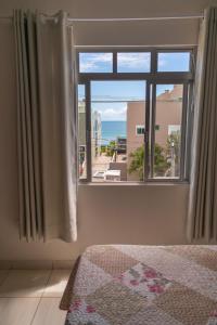 a bedroom with a window with a view of the ocean at Edifício Iris - Bombinhas in Bombinhas