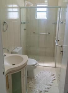 y baño con ducha, aseo y lavamanos. en Edifício Iris - Bombinhas, en Bombinhas