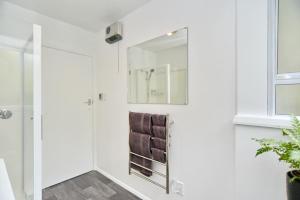 a bathroom with a mirror and a brown leather chair at Bevington - Christchurch Holiday Homes in Christchurch