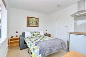 a bedroom with a bed and a desk and a kitchen at Bevington - Christchurch Holiday Homes in Christchurch