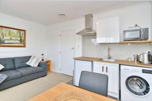 a living room with a couch and a kitchen at Bevington - Christchurch Holiday Homes in Christchurch
