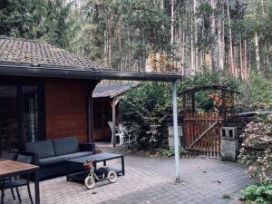 un patio con sofá, mesa y mesa de picnic en Chalet in a peaceful location in a forest near Nijlen, en Nijlen