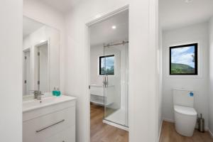 a white bathroom with a sink and a toilet at Lake Days - Omori Holiday Home in Kuratau