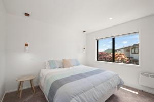 a white bedroom with a bed and a window at Lake Days - Omori Holiday Home in Kuratau