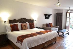 a bedroom with a large bed and a couch at Hotel Casa Rosada - Adults Only in San Miguel de Allende