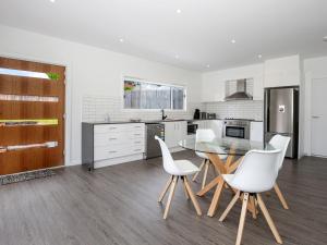 a kitchen with a glass table and white chairs at Scribbly Gum I Pet Friendly I 15 Mins Drive to Hyams Beach in St Georges Basin