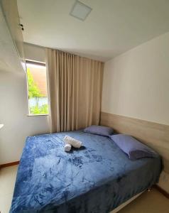 1 dormitorio con 1 cama azul con 2 almohadas y ventana en Solaris Village Imbassaí, en Salvador