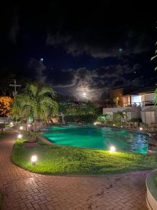 una piscina por la noche con palmeras y un edificio en Solaris Village Imbassaí, en Salvador