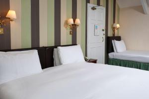 a bedroom with a large white bed and a door at Best Western The George Hotel, Swaffham in Swaffham