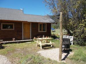 una cabaña de madera con una mesa de picnic frente a ella en La Holandesa B & B en Villa Meliquina